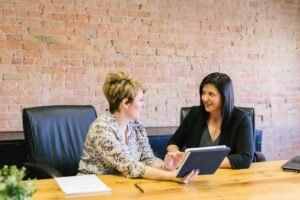 Two women in a therapy session sitting on chairs in a warm counseling office